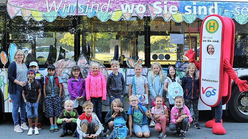 Malwettbewerb Grundschüler Schledehausen vor Bus mit VOS Maskottchen Haltelinchen.