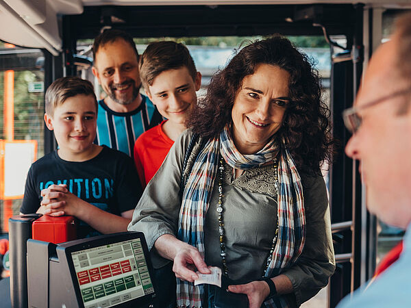 Familie steigt in den Bus. Busfahrer kontrolliert Tickets 