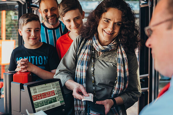 Familie im Bus kauft Ticket beim Busfahrer