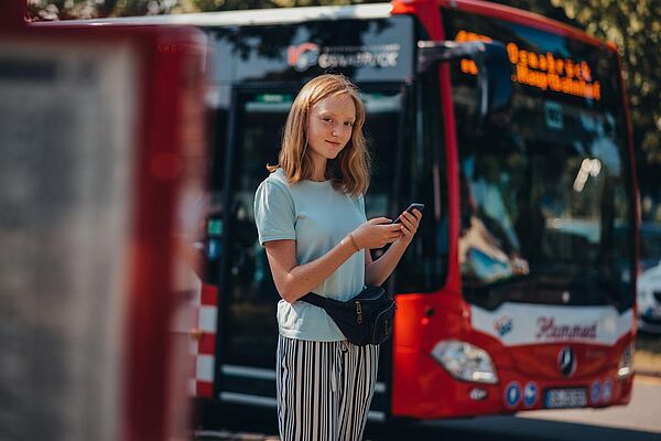 Mädchen mit Handy vor dem Bus