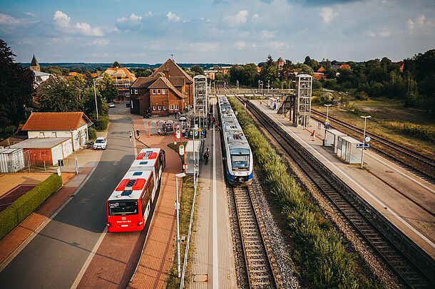 Bus und Zug treffen an Bahnhof aufeinander, Blick von oben.