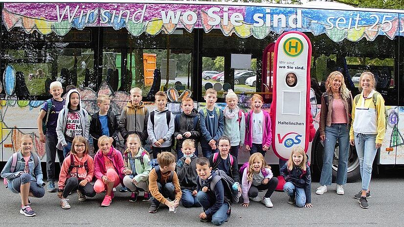 Malwettbewerb Grundschüler vor Bus mit VOS Maskottchen Haltelinchen.