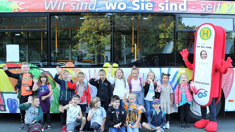 Malwettbewerb Grundschüler Belm vor Bus mit VOS Maskottchen Haltelinchen.