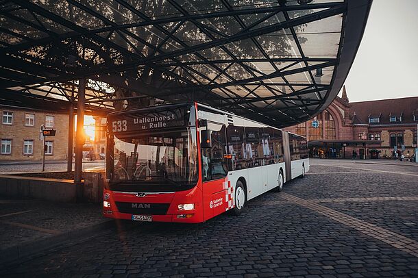 VOS-Bus am Bahnhof im Abendlicht vor dem überdachten Bahnsteig