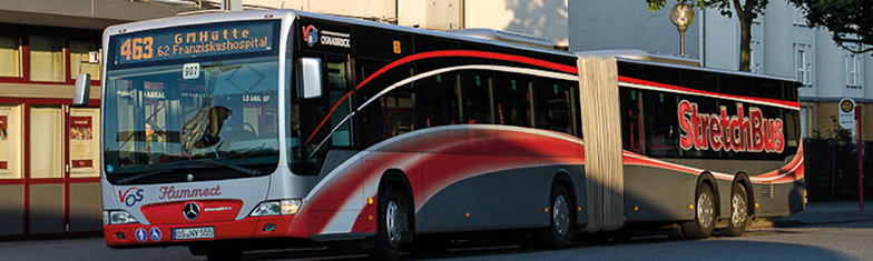 Gelenklinienbus an einer Haltestelle mit seitlichen roten Streifen und Schriftzug StretchBus.