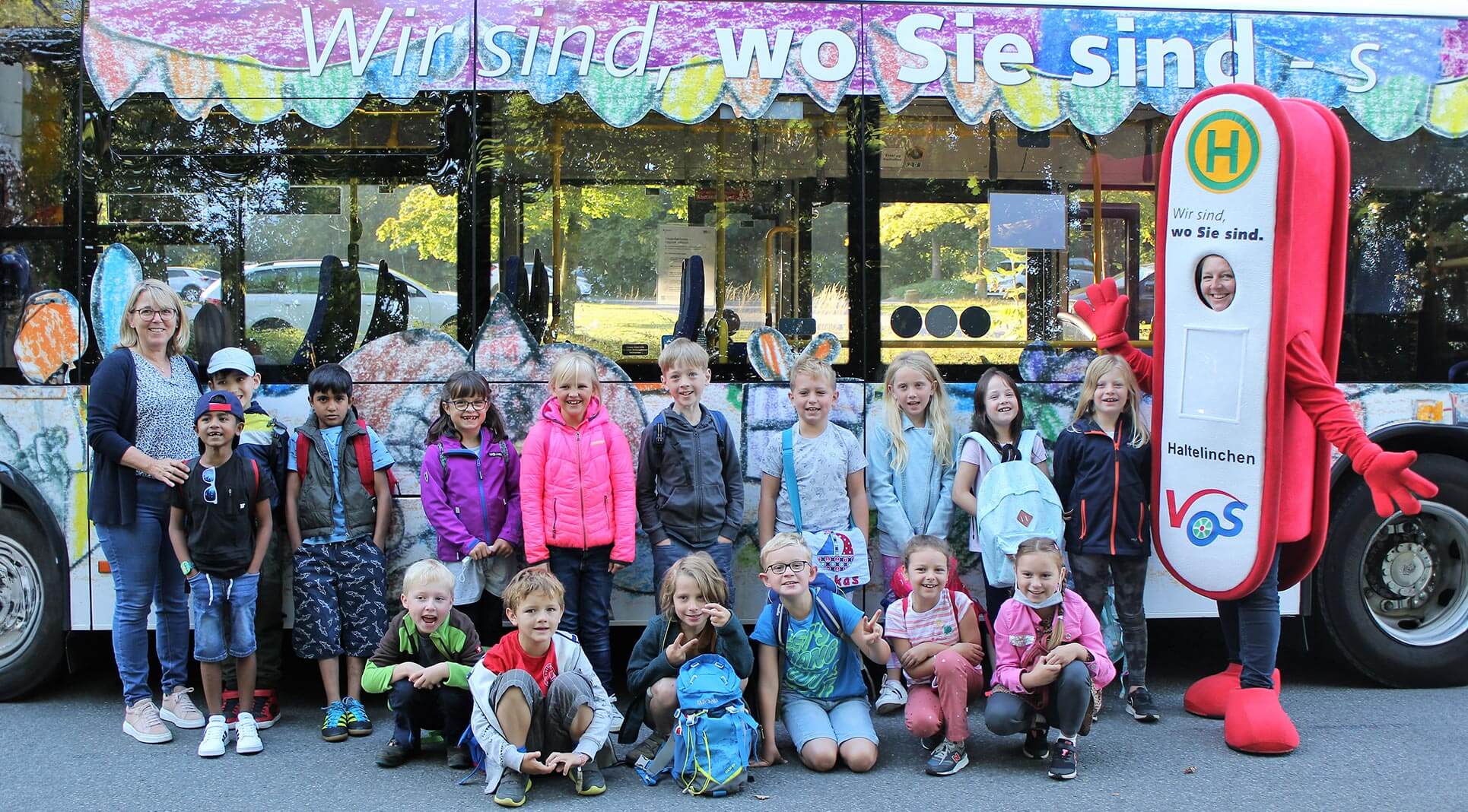 Die i - Männchen Grundschüler aus Schledehausen stehen vor einem bunt gestaltetem Linienbus.