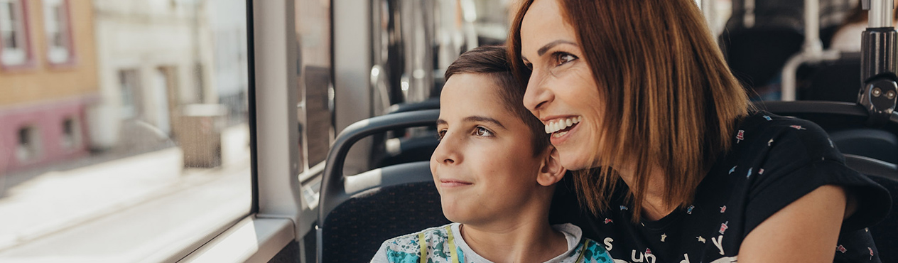 Eine Mutter mit ihrem Kind sitzen im Bus und schauen zum Fenster hinaus.